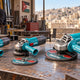 Three angle grinders, 115mm, 125mm and 230mm, on a steel workbench with cutting discs